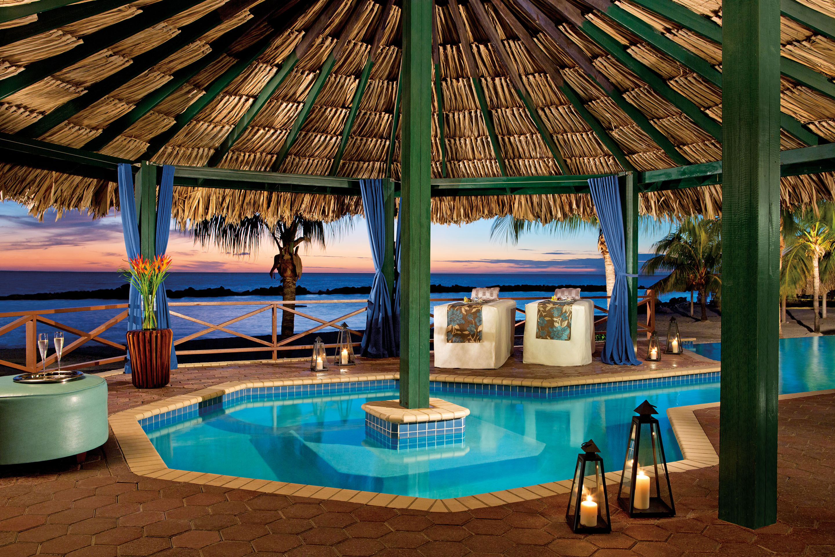 Romantically lit, secluded spa villa with couple's massage tables overlooking the ocean.